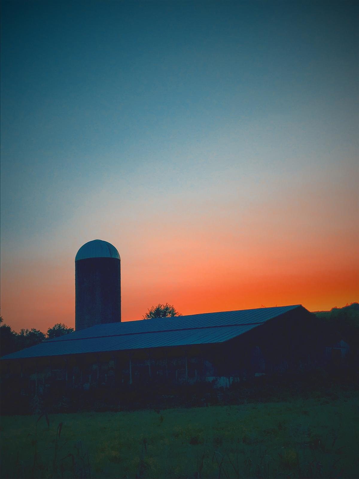 Silo in silhouette against a warm dusk sky