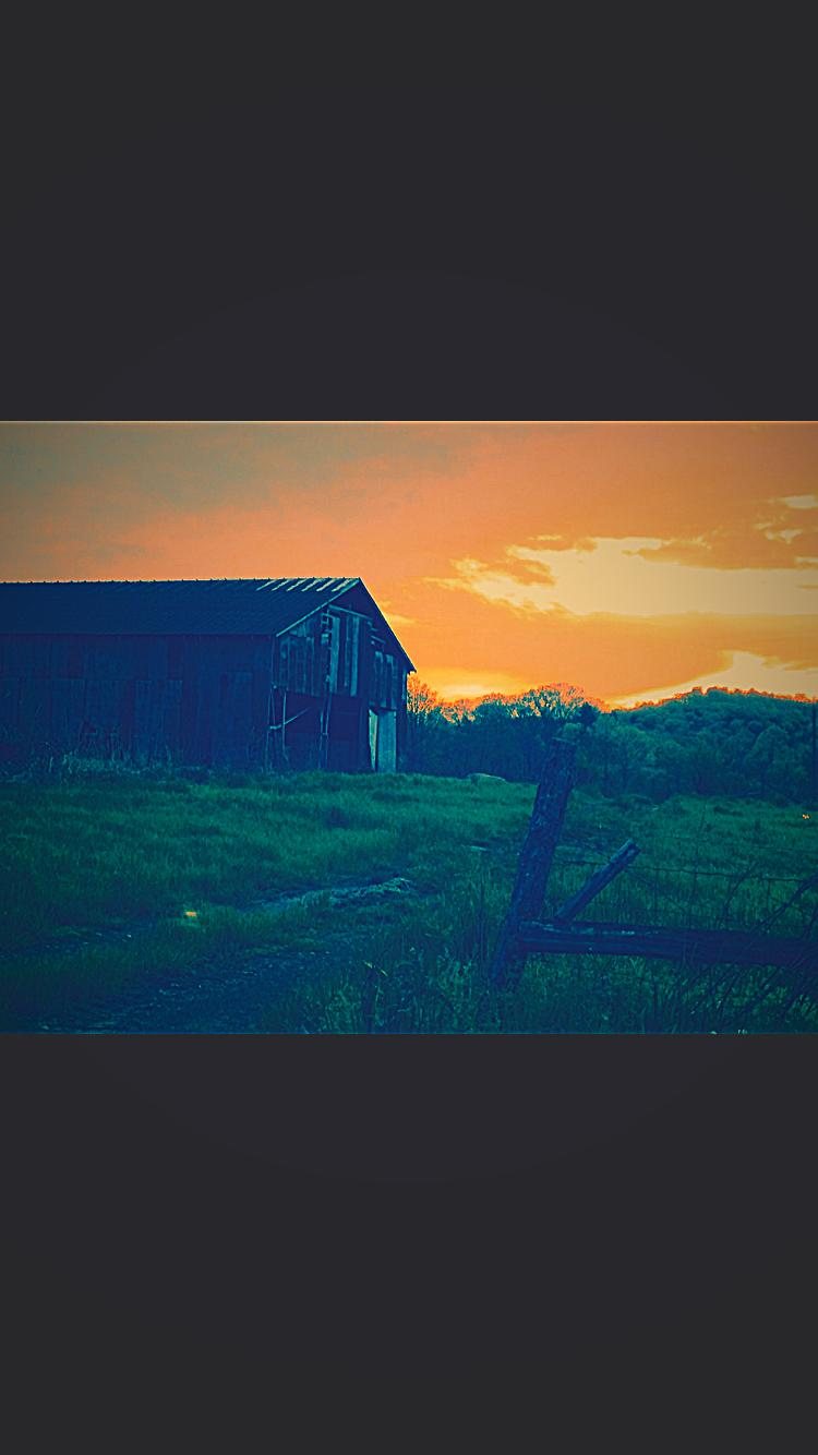 Farm building silhouetted at sunset